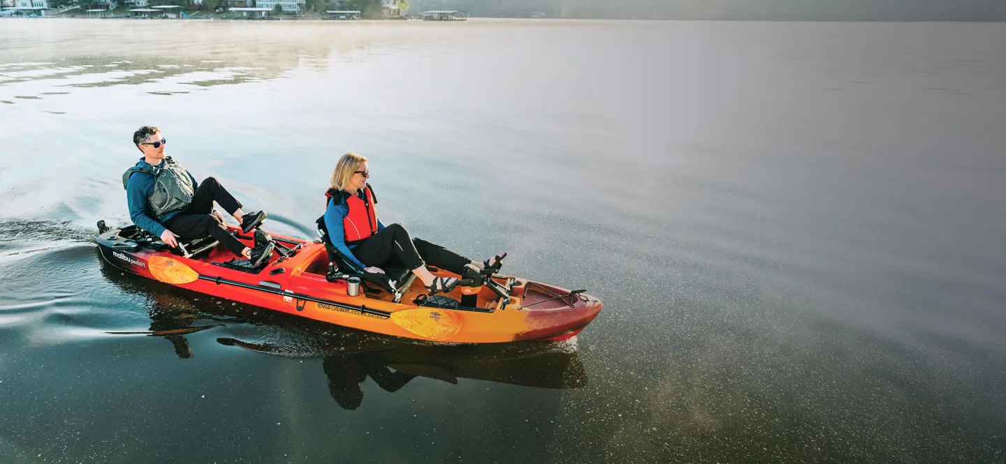Man and Woman pedaling in the Old Town Ocean Kayak Malibu Pedal T kayak on the water